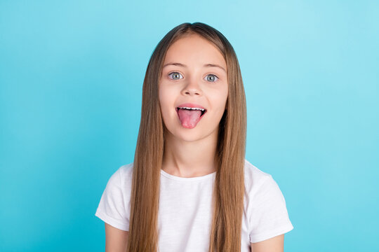 Photo of cute brown hair small girl tongue out wear white t-shirt isolated on blue color background