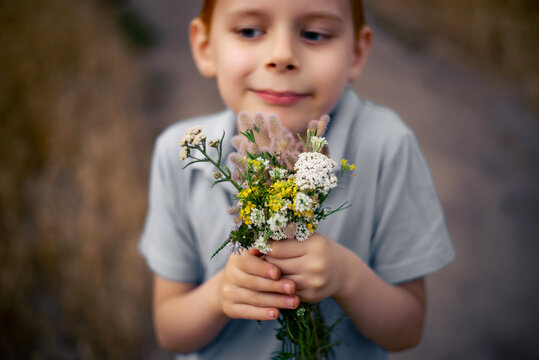 a bouquet of wild flowers in the hands of a 7-year-old boy