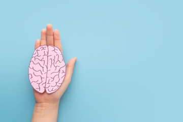 Woman hands holding human brain shape made from paper on light blue background. Awareness of Alzheimer, Parkinson's disease, dementia, stroke, seizure or mental health. Neurology and Psychology care. - obrazy, fototapety, plakaty