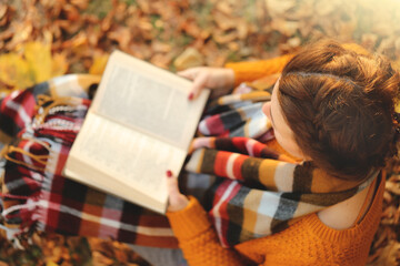Reading books. Learning and knowledge concept. A girl with an open book in an autumn garden in the rays of the sun.Autumn books. Student with a book. View from above.