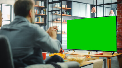 At Home Man Sitting on a Couch Watch Green Screen Chroma Key TV. Middle Aged Male Resting, Watches...