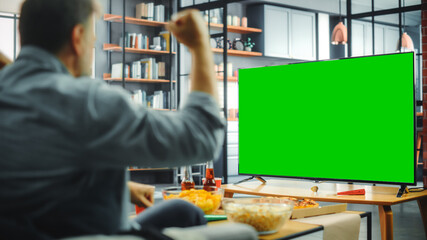 At Home Man Sitting on a Couch Watch Green Screen Chroma Key TV. Middle Aged Male Resting, Watches...
