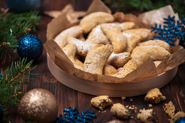 Obraz na płótnie Canvas Homemade Christmas nuts cookies vanilla crescent with sugar powder in Christmas decorations. New Year and Christmas celebration concept. Copy space. Soft focus. Flying sugar powder
