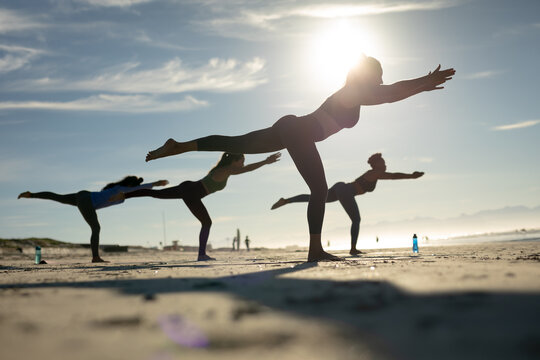 Group of diverse female friends practicing yoga at the beach