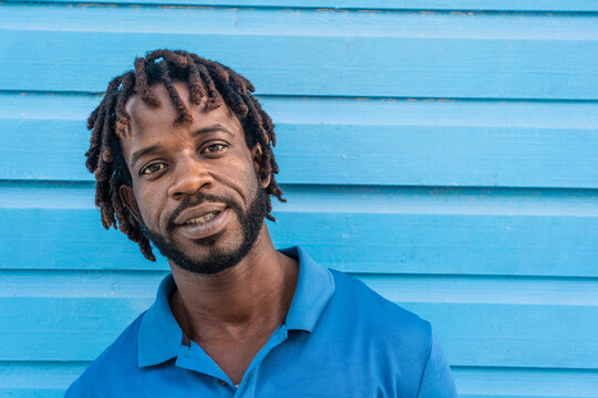 Dominican Republic. Close-up face of smiling young African American against blue wall. Portrait of a happy man. Dominican people.