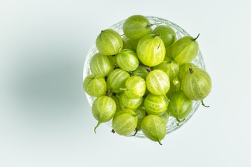 Freshly picked gooseberries in bowl on plain background