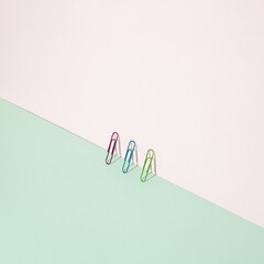 Office color paper clips on pastel pink background. Minimal concept art.