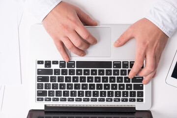 Fototapeta na wymiar close up of male hands typing on laptop keyboard while working at white desk