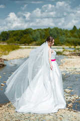 Fototapeta na wymiar Fashion bride posing on mountain river. Wedding day