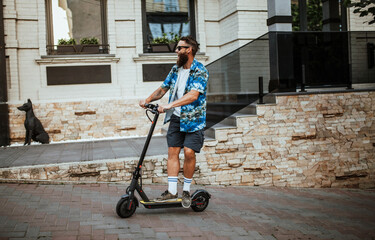 Young hipster man driving electric scooter in bright sunny day. Ecological transportation concept.
