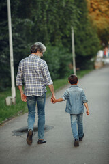 Grandfather with grandchild walking in a summer park