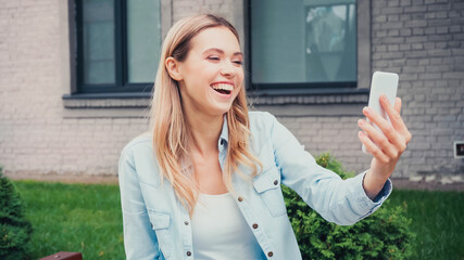 Fototapeta premium cheerful student having video call on smartphone near building