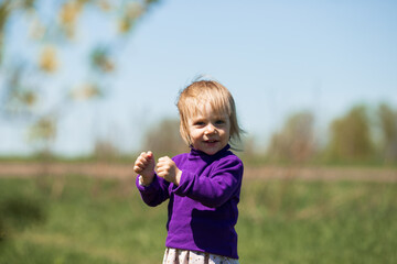 Fototapeta premium a little girl in purple clothes looks and laughs
