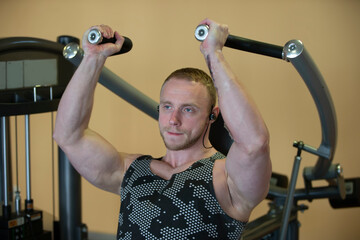 A handsome man of an athletic physique is engaged on the simulator.