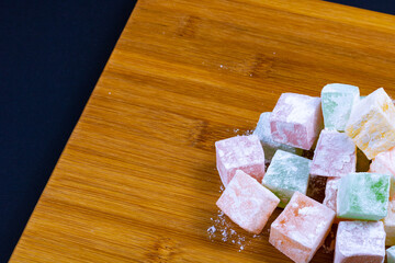 Turkish Delights on the wooden plate isolated on black background. Ramazan bayrami (eid al fitr) and Kurban bayrami (eid al adha) background photo. Turkish delight (lokum). Eid mubarak - iyi bayramlar
