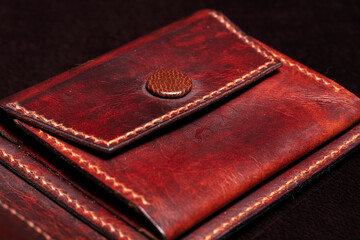 Leather wallet brown wallet with a button fastener on a dark background.
