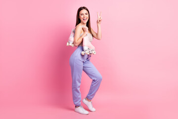 Full size photo of young beautiful happy excited funky girl show v-sign hold rollers isolated on pink color background
