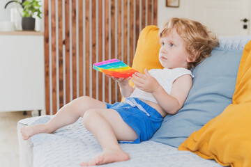 little boy holding anti stress sensory pop it toys in his hand