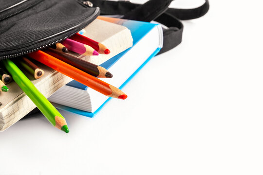Open school backpack on an white background. Books, a notebook and pencils are sticking out of an open school backpack. Education concept.