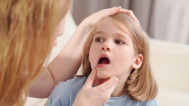 Little girl shows mother reeling tooth. mom inspects baby's mouth
