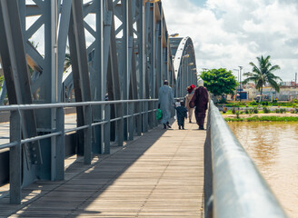 Local people walking on old the metallic arched bridge over the senegal river, called 