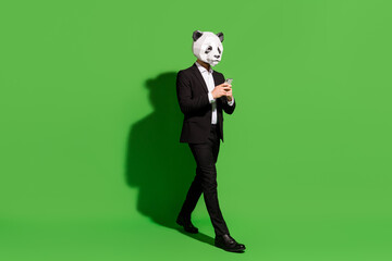 Photo of traveler china blogger walk hold telephone wear panda mask black tux shoes isolated on...