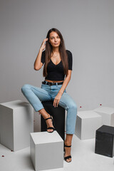 female model in re skirt and denim jeans poses for the camera on black and white cubes