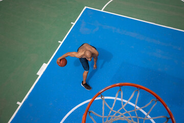 High angle view of young man, male basketball player playing basketball at street public stadium,...