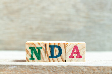 Alphabet letter block in word NDA (Abbreviation of Non disclosure agreement) on wood background