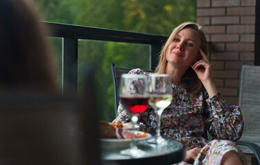 Two friends are drinking wine on the balcony on vacation.