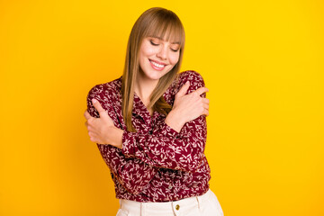 Photo portrait of blonde woman dreaming hugging herself in printed blouse smiling isolated bright yellow color background