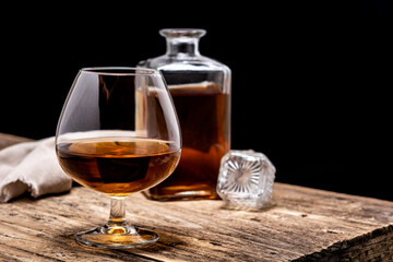 Cognac drink on rustic wooden table and black background. Copy space