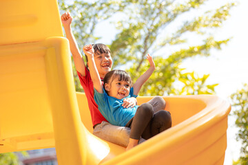 Fototapeta na wymiar Cute little girls siblings having fun on playground outdoors on sunny summer day. Children on plastic slide. Fun activity for kid. active sport leisure for kids