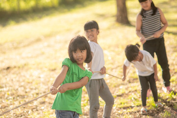 Children playing tug of war at the park on sunsut