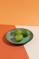 Limes on the green plate. Minimal layout on the earthy orange and neutral tone colours of the...