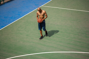 One african-american male basketball player playing at street public stadium, sport court or palyground outdoors. Concept of healthy active lifestyle, motion, hobby.