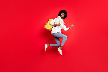 Fototapeta na wymiar Full size profile photo of impressed wavy hairdo student lady run with backpack wear white sportswear jeans isolated on red color background