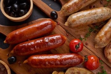 sausages and ingredients for cooking. Grilled sausage with the addition of herbs and and spices, vegetables, rosemary, thyme on the grill plate, Grilling food, bbq, barbecue, on stone table. Top view.