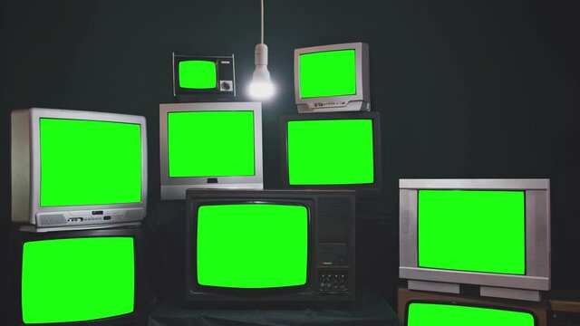 Nine Vintage Televisions turning on Green Screens on a Retro TV Wall. Dark Tone. Zoom In. 4K Resolution.