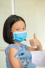 little girl in face mask in doctor's office is vaccinated. syringe with vaccine for covid-19...