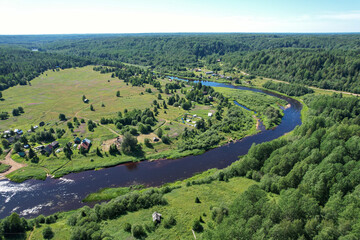 aerial view river flowing village by the river in the middle of the forest river bend houses and agricultural field