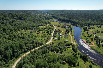 Fototapeta na wymiar aerial view river flowing village by the river in the middle of the forest river bend houses and agricultural field