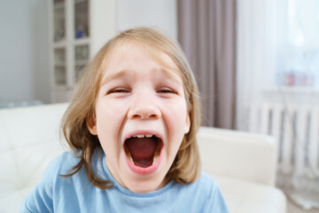 Funny little girl screams with her mouth wide open. joy