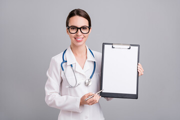 Photo portrait young nurse with sthethoscope smiling keeping pen clipboard isolated grey color background