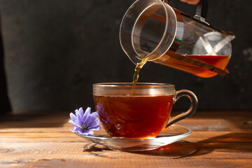 a glass mug with a chicory drink. A blue chicory flower floats in a cup with a drink