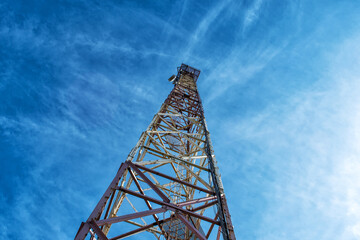 Metal tower for mobile communications, against the blue sky. Bottom view.