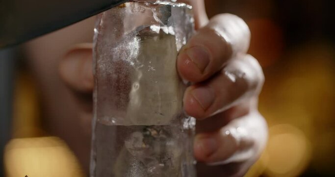 Bartender makes crushed ice from large ice cube by sharp knife, making the cocktail on the bar counter, refreshing cold drinks, 4k Prores HQ 120fps