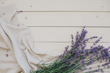 Bunch of lavender and linen fabric on white wooden background.