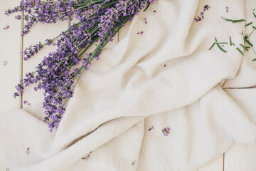 Bunch of lavender and linen fabric on white wooden background.