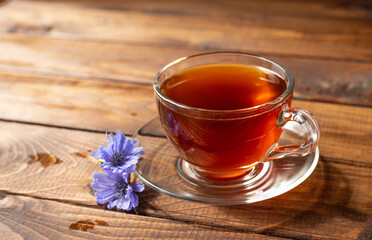 a glass mug with a chicory drink. A blue chicory flower floats in a cup with a drink